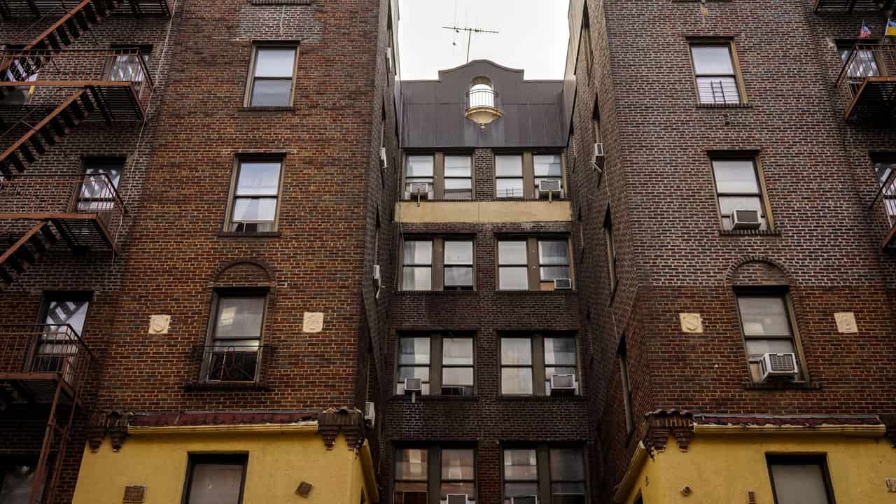Low-angle view of urban brick apartment buildings with fire escapes, embodying classic city architecture.