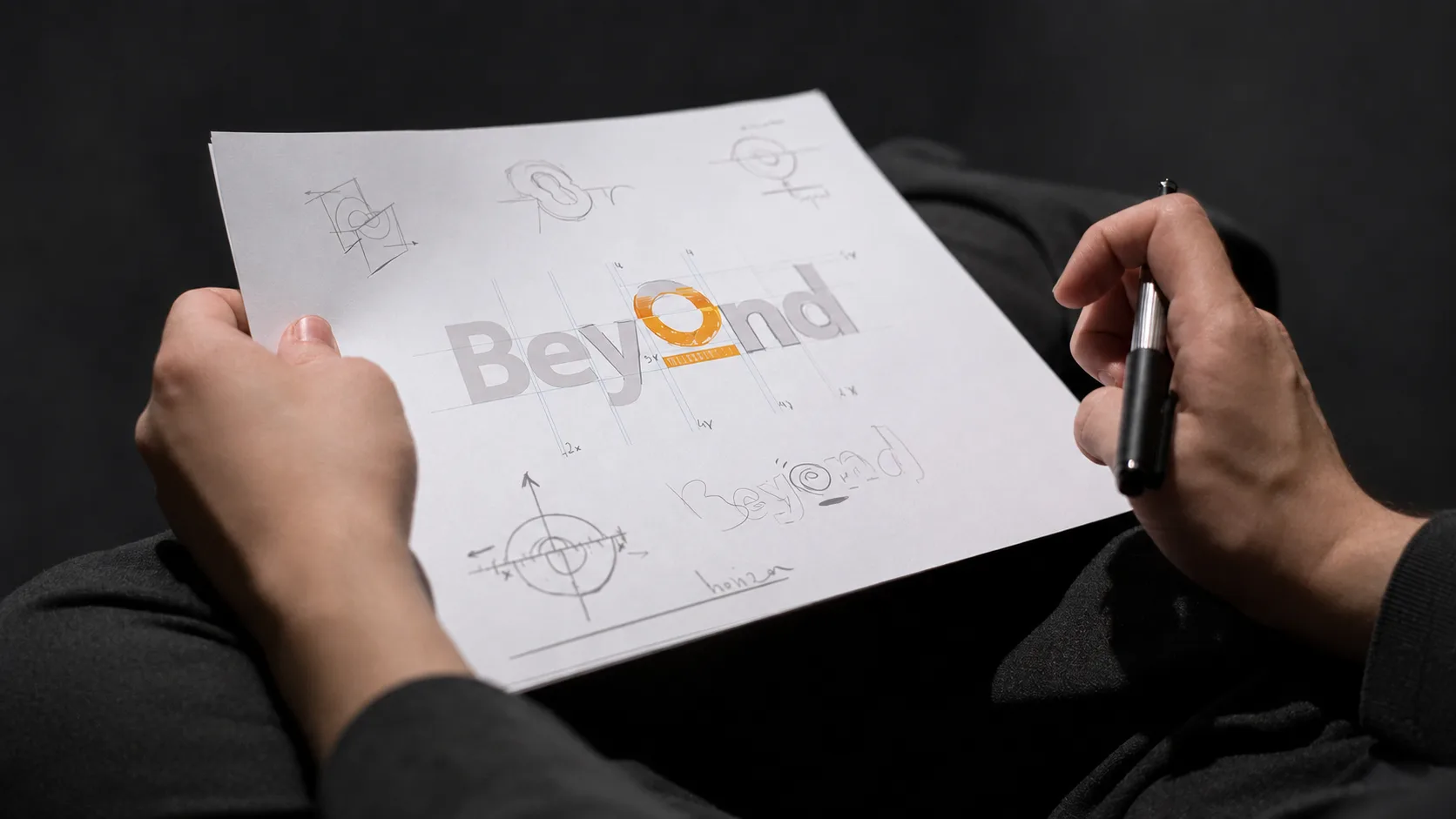 Designer holding a sheet of early IKEA Beyond logo sketches and construction studies.