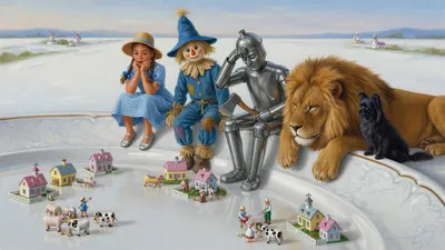 A braided girl, a scarecrow, a tin man, a lion, and a small dog sit in a row on a white wall looking down at miniature brightly painted china houses, barns, and tiny china people on a platter-smooth white floor.
