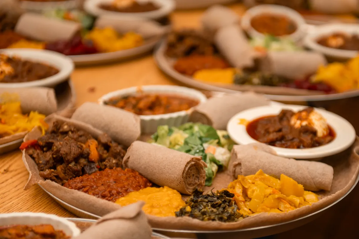 Colorful Ethiopian platters featuring injera, spiced meats, lentils, and fresh greens, perfect for sharing.