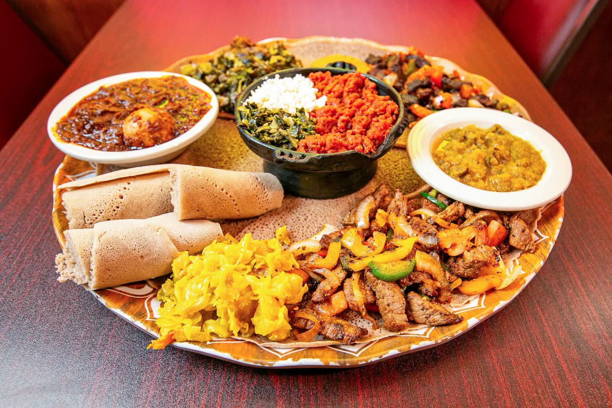 Savory Ethiopian platter featuring spicy stews, injera, grilled meats, and vibrant vegetable dishes.