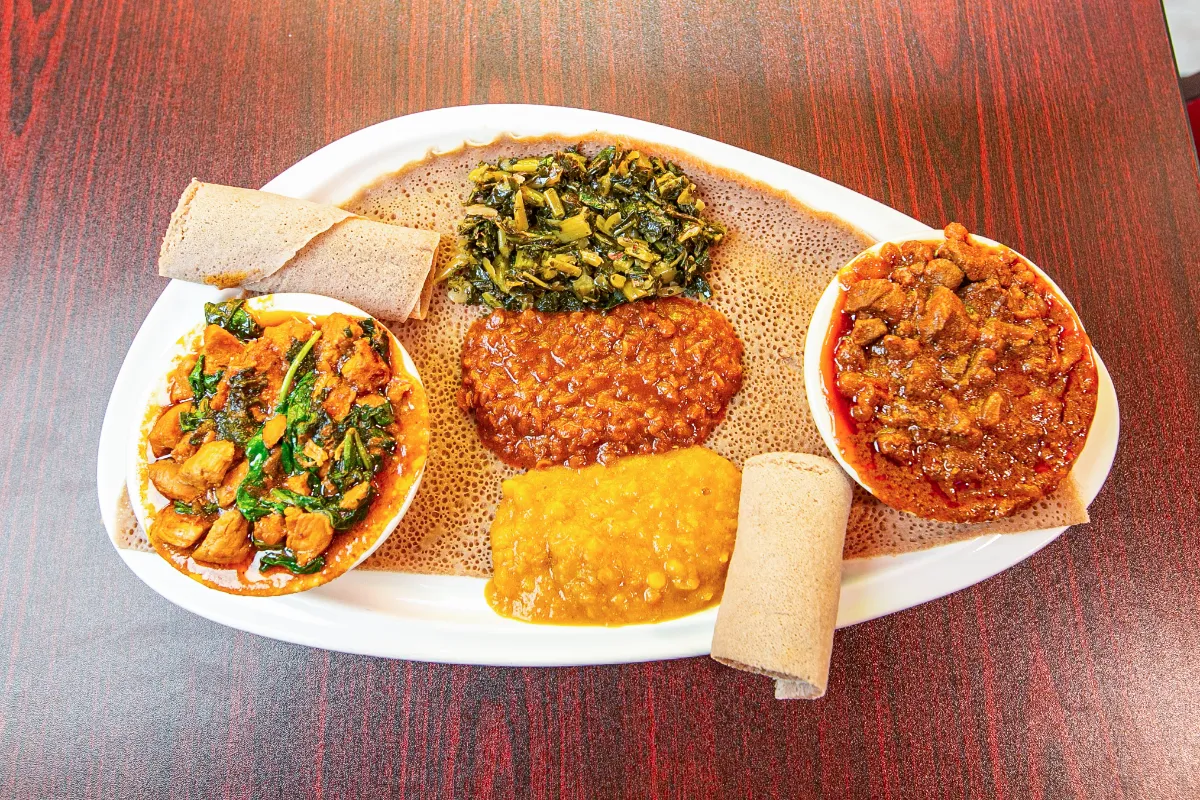 Vibrant Ethiopian platter featuring flavorful stews, lentils, and injera on a traditional woven basket.