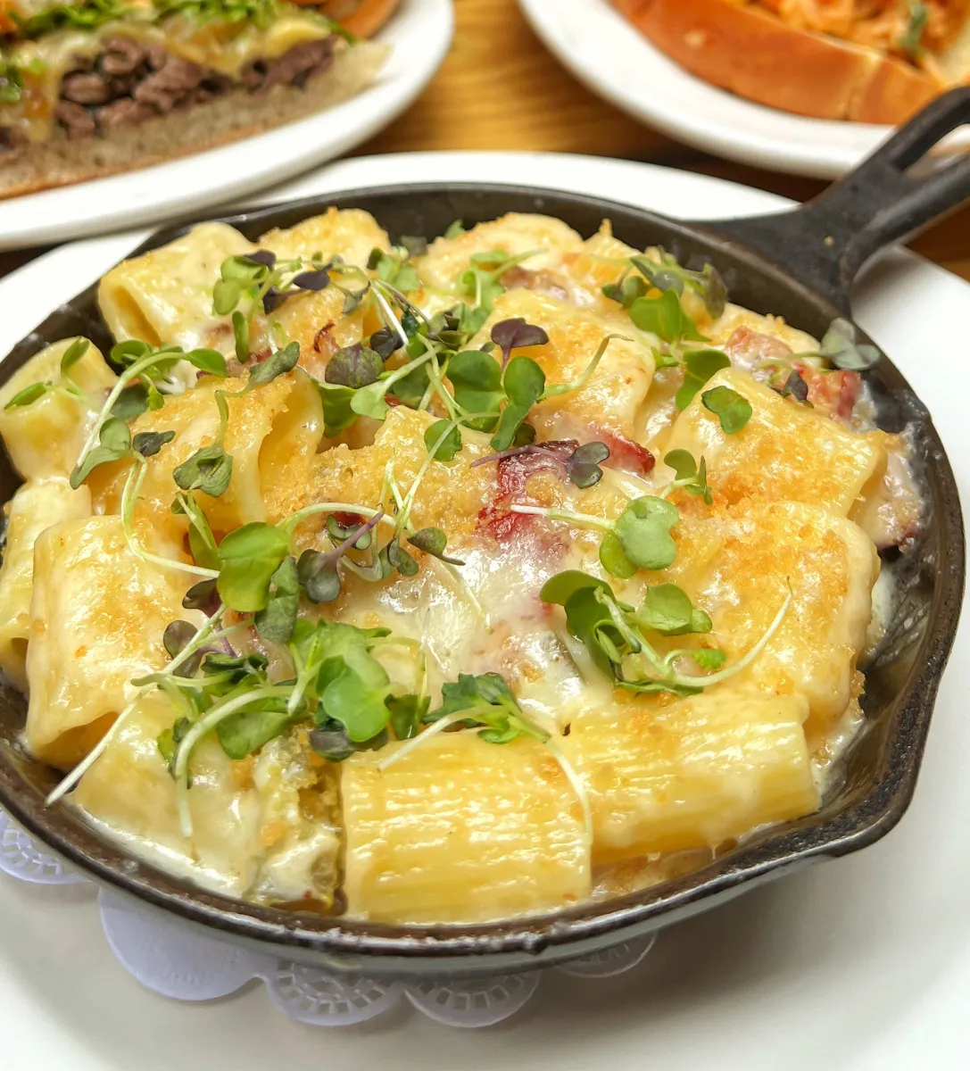 Delicious Lobster Mac & Cheese from Loreley Beer Garden in NYCs Lower East Side, featuring creamy cheese and succulent lobster topped with microgreens. Perfect for birthdays, engagements, and corporate events. Enjoy this popular dish in the vibrant atmosphere of the Lower East Side and surrounding areas like the Bowery