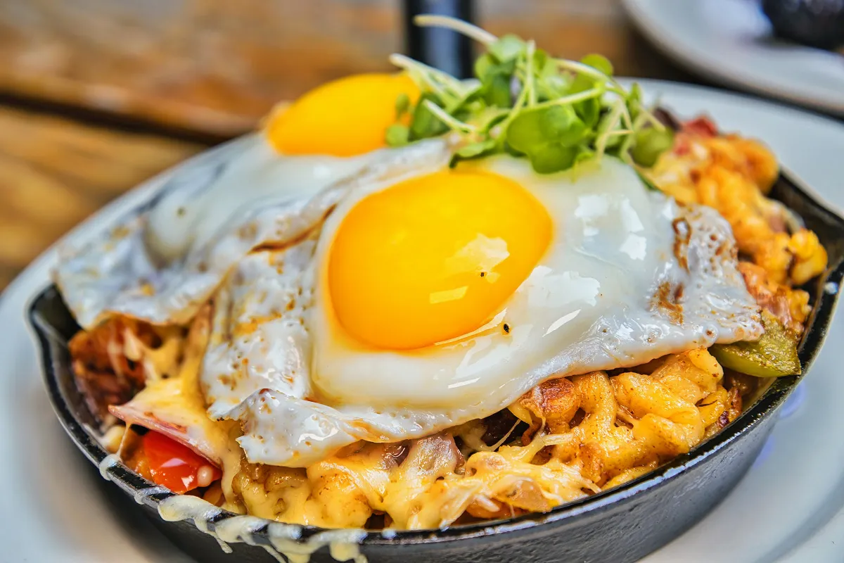 Delicious skillet of Breakfast Käse Spätzle topped with two sunny-side-up eggs, served at Loreley Beer Garden in the Lower East Side, NYC 10002, near SoHo, Greenwich Village, and East Village. Enjoy this savory dish at one of the best German restaurants in New York