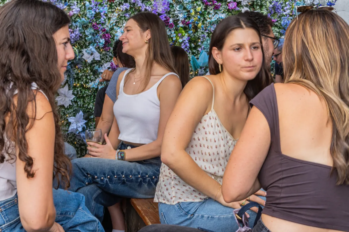 People enjoying a vibrant and lively atmosphere at Loreley Beer Garden in NYC, surrounded by a floral backdrop. Ideal spot for social gatherings in the Lower East Side and nearby areas like Soho and Chinatown.