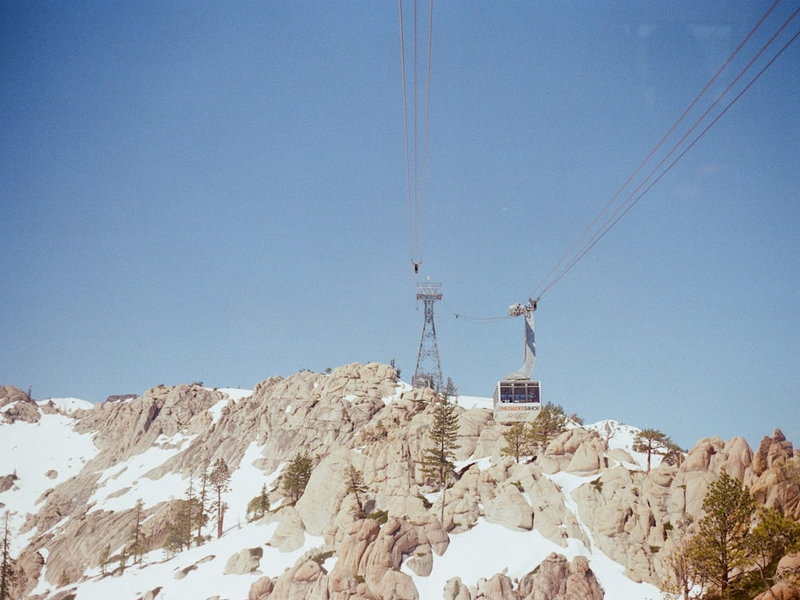 Sunny blue sky day with snow covered mountains and a cable car tram