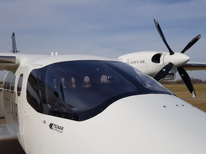 The front of the Alpen Air´s Tecnam P2012 Traveller aircraft on a field.