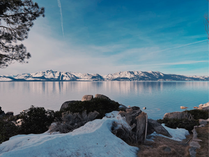 a snowy landscape with a body of water and mountains in the background