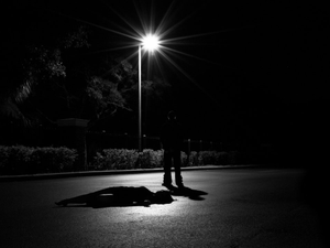 a person laying on the ground under a street light