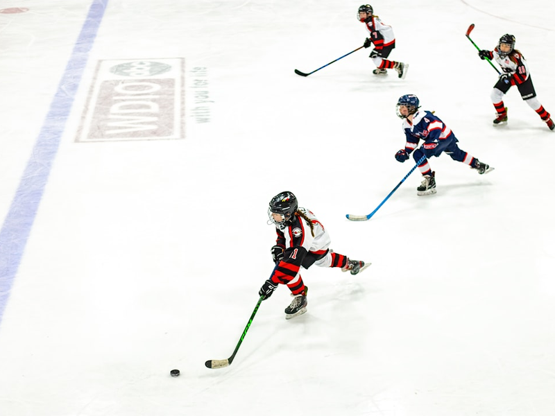 a group of young children playing a game of ice hockey