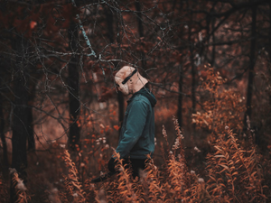 a person walking through a forest with a hat on