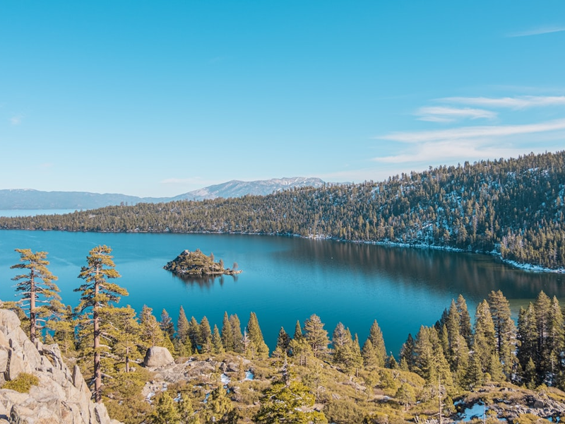 blue lake surrounded by green trees under blue sky during daytime