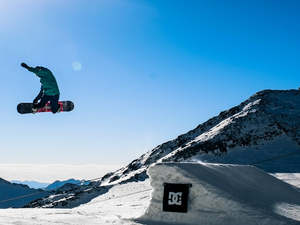person in green jacket and black pants riding black snowboard on snow covered mountain during daytime