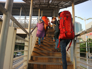 People are walking up stairs with heavy backpacks.