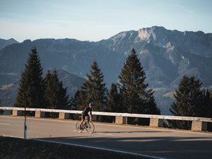 a person riding a bike on a road with mountains in the background