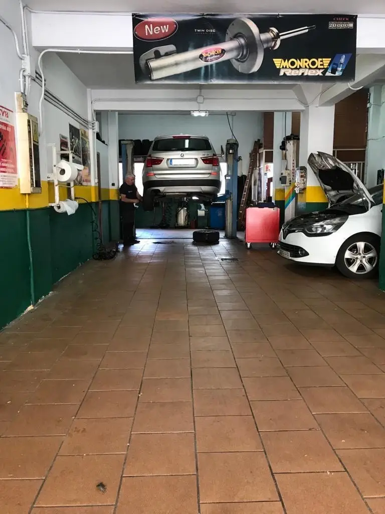 Interior del taller mecánico Eurobox en Oviedo con un coche en el elevador