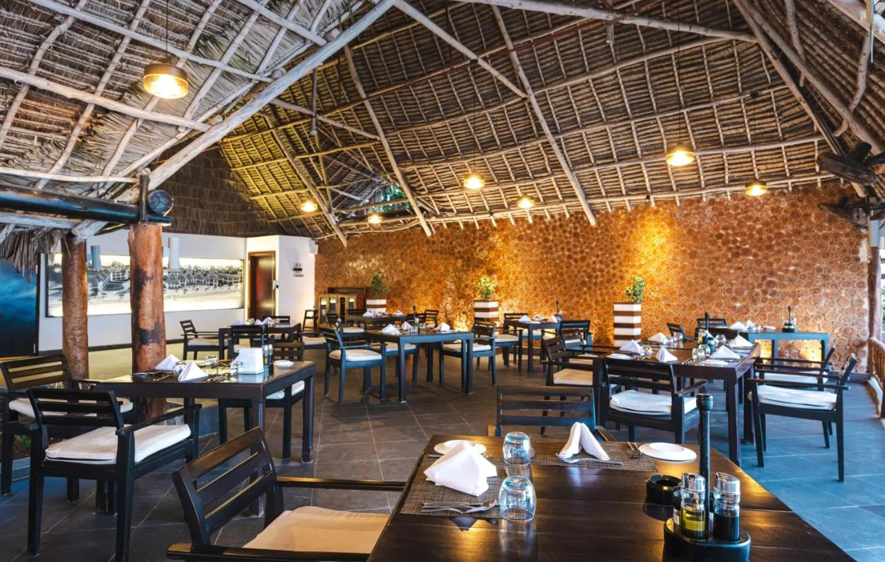 Spacious restaurant interior with traditional thatched roof and warm lighting.