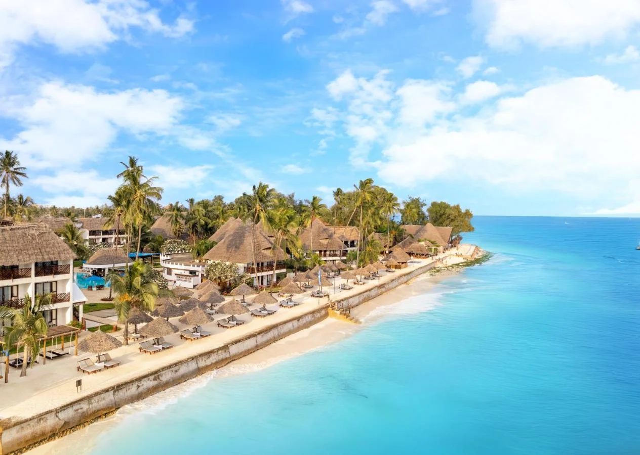 Scenic view of palm trees, resort villas, and turquoise ocean in Zanzibar.