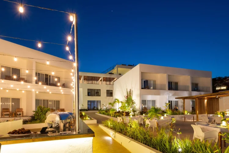 Warmly lit resort exterior and outdoor seating area during evening twilight.