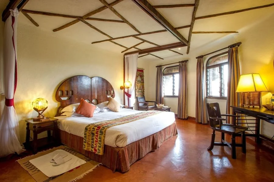 Spacious king room at Serengeti Serena Safari Lodge with African-inspired decor, warm lighting and a comfortable safari-style bed.