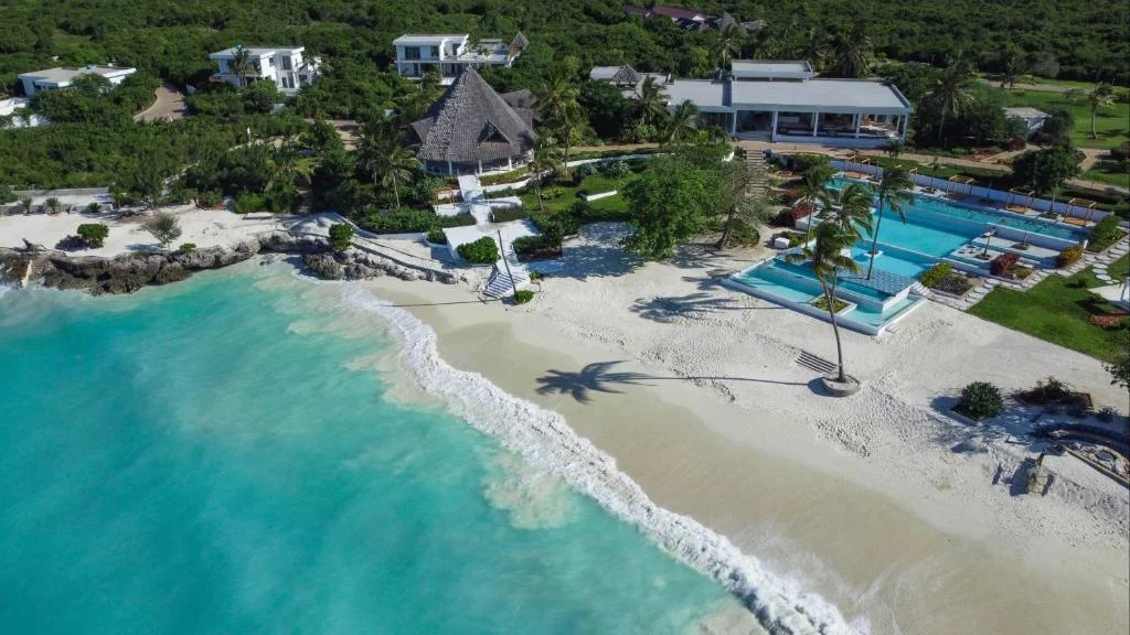 Aerial drone view of the beachfront resort, pool, and white sand coastline
