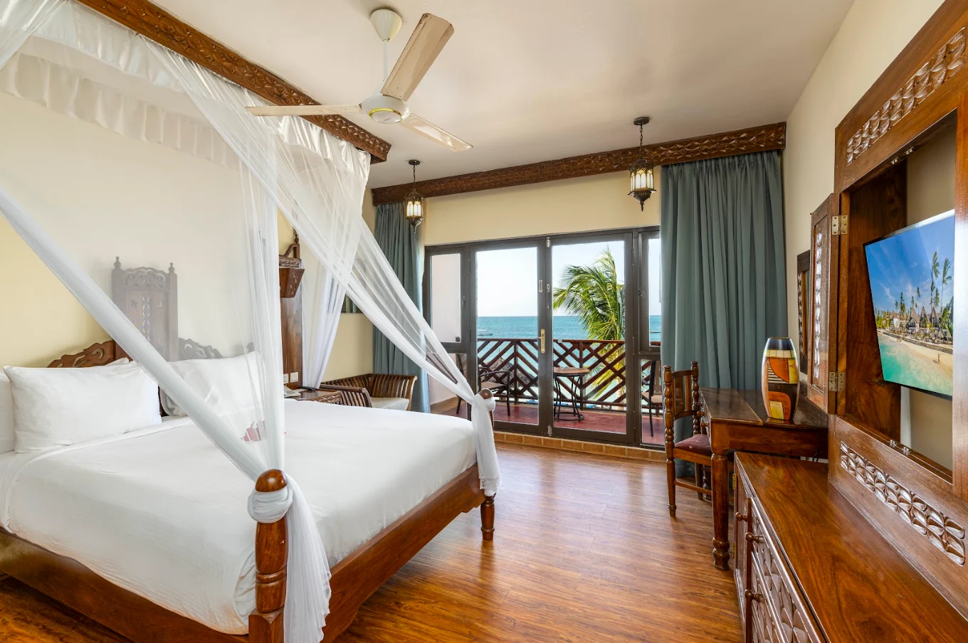 Elegant hotel bedroom suite with canopy bed and balcony ocean views at Nungwi Beach Resort.