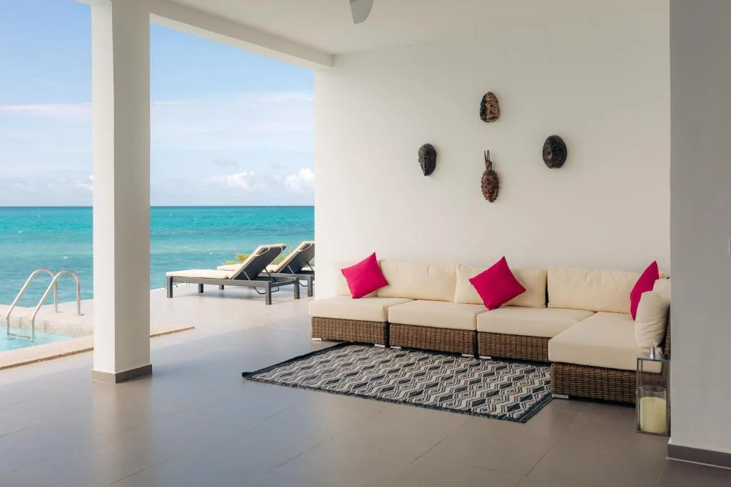 Elegant cream sofa with pink cushions facing the turquoise ocean in Zanzibar.