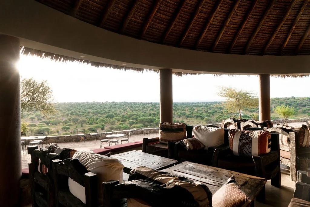 Thatched-roof safari curio gift shop with guests browsing handmade Tanzanian crafts in Tarangire.