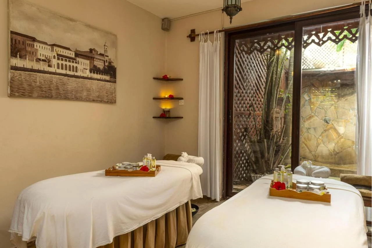 Relaxing spa treatment room with massage tables and natural wood decor.