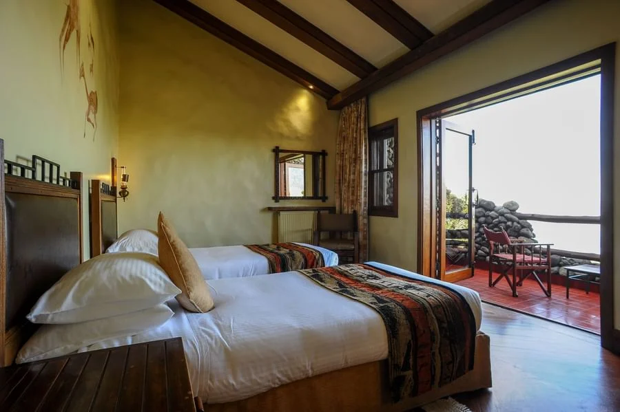 Deluxe double room with wooden ceilings and glass doors opening to a private crater view terrace
