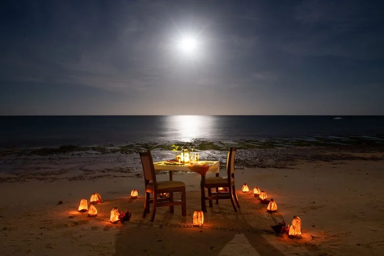 Romantic candlelit dinner setup on the beach under a starry sky in Zanzibar.