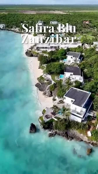 Vertical drone shot of luxury resort villas lining the crystal-clear water.