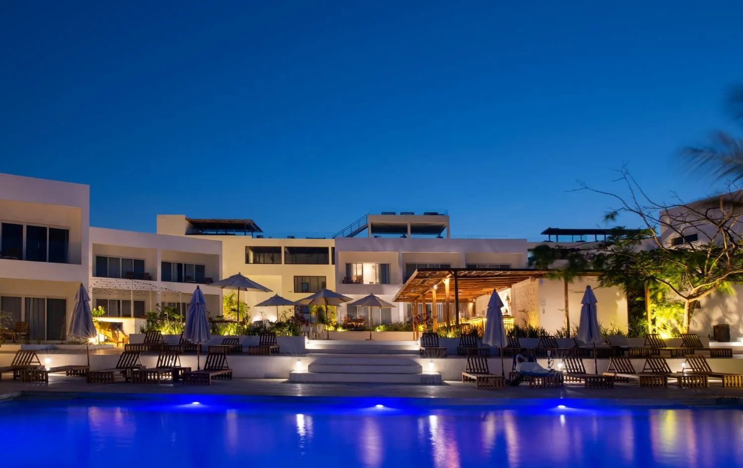 Illuminated resort swimming pool and hotel exterior glowing at night in Zanzibar.