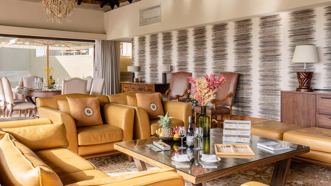 Modern safari lodge lounge with plush leather armchairs, wooden coffee tables, and elegant decor in Serengeti.