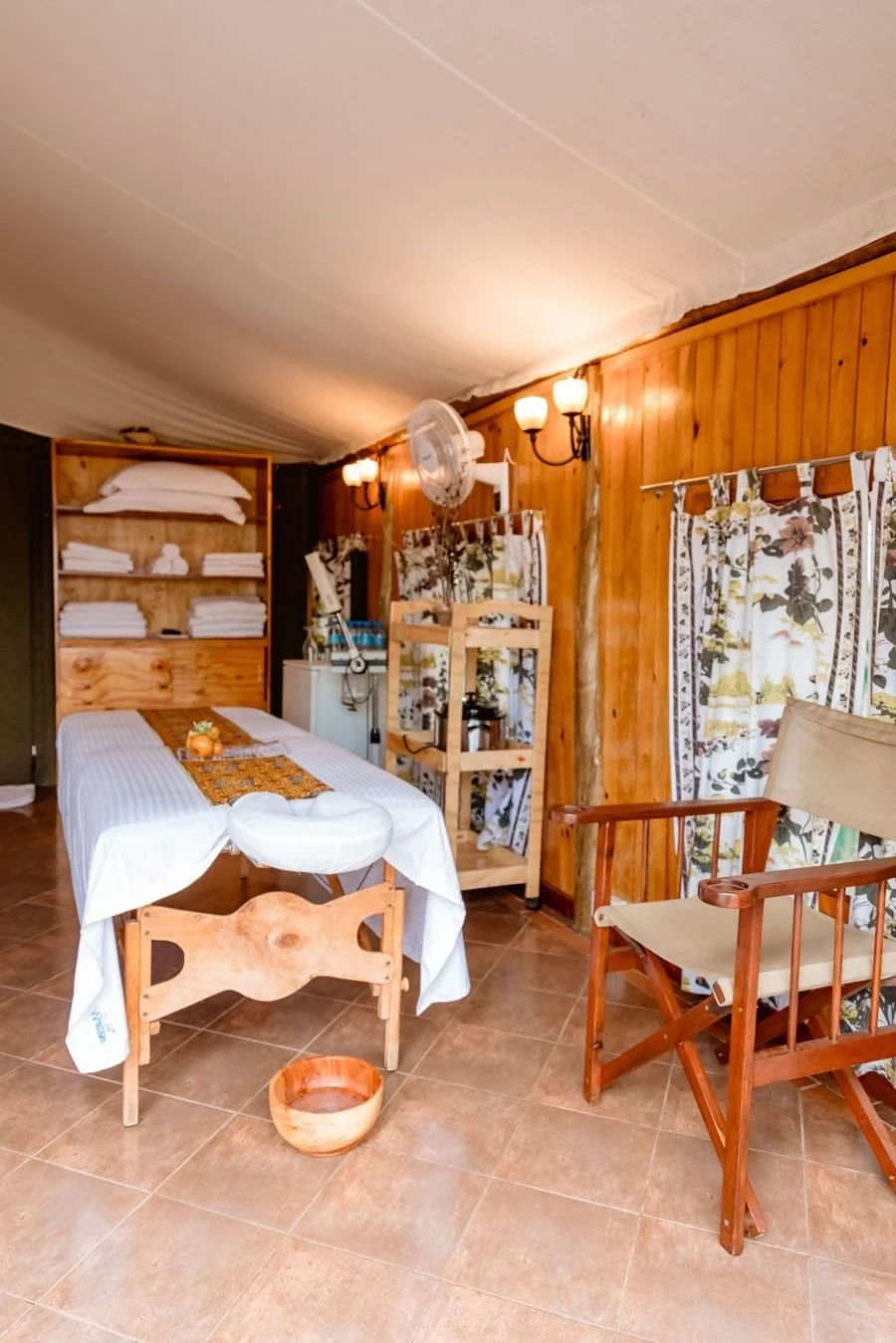 Spa treatment room at Serengeti Serena Safari Lodge with a massage bed, wooden walls, towels and a calm relaxing interior.