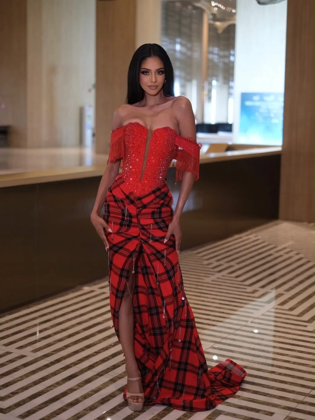 Jihan Dimack posing in an off-the-shoulder red plaid corset dress with a thigh-high slit.