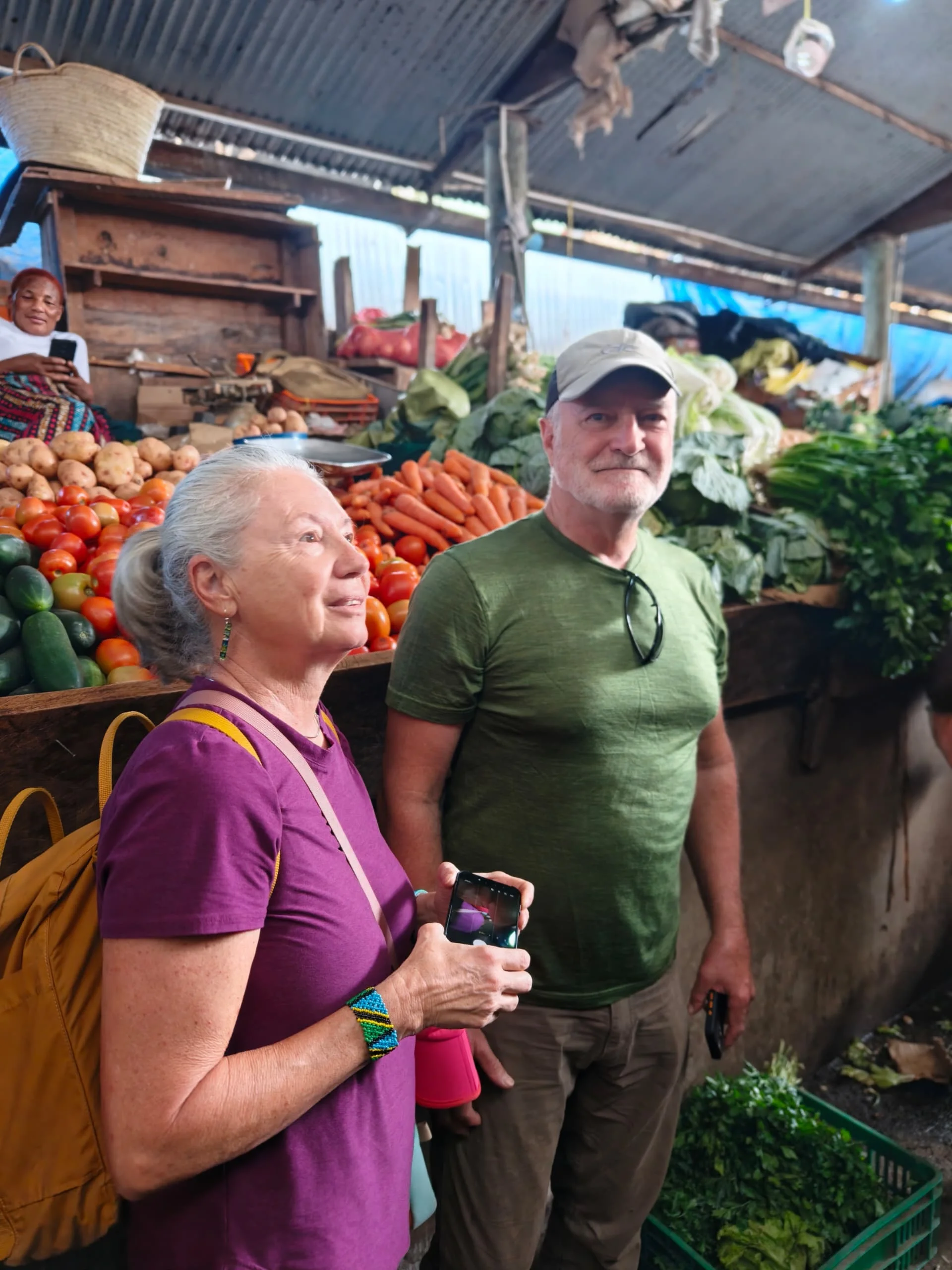 Tourist couple posing inside a covered fruit and vegetable section of Arusha Central Market.