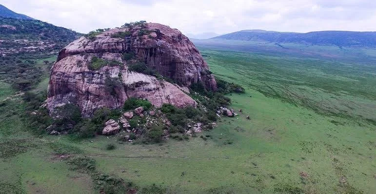 Aerial landscape view of a massive rock outcrop amidst green plains near Olkarien Gorge, Tanzania.