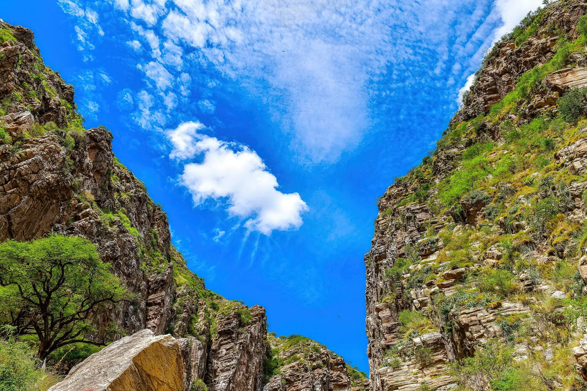 Sunlit blue sky shining above massive rock formation cliffs at Olkarien Gorge, Tanzania.