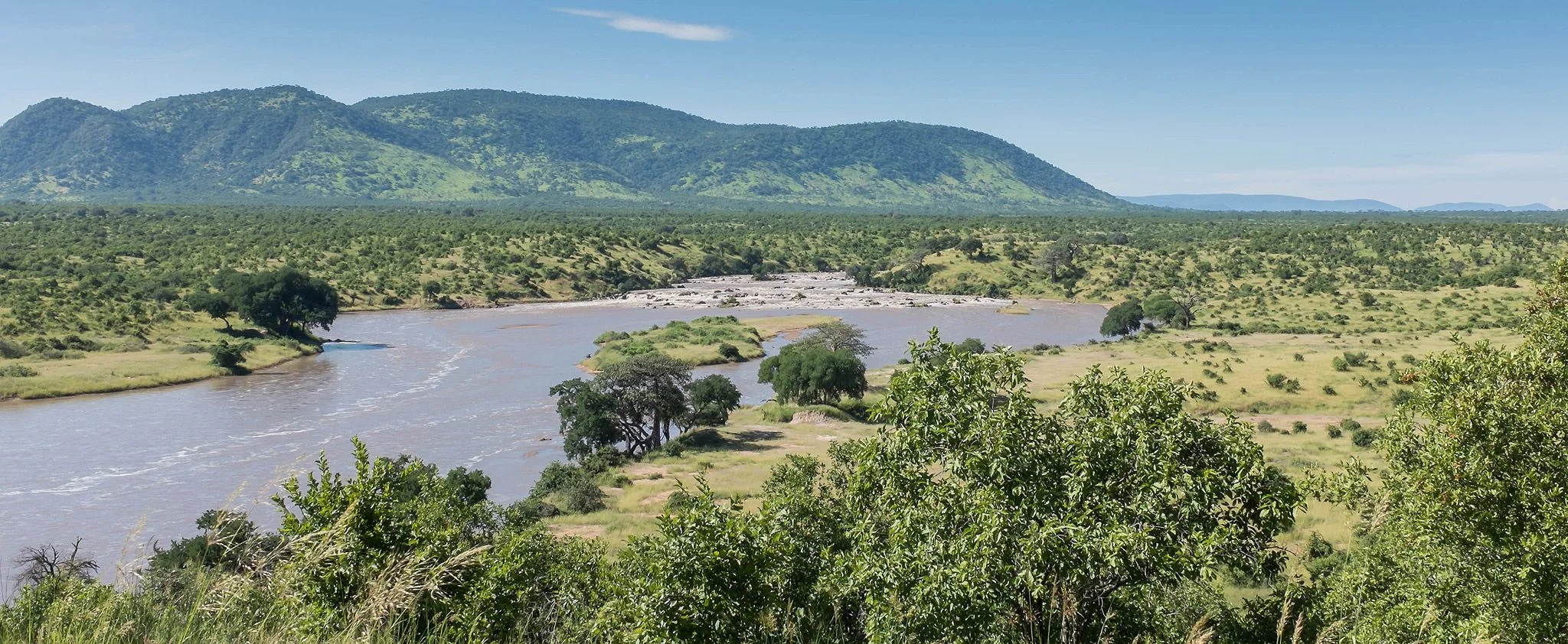 Overlook of a wide river valley framed by green hills and dense bushland.