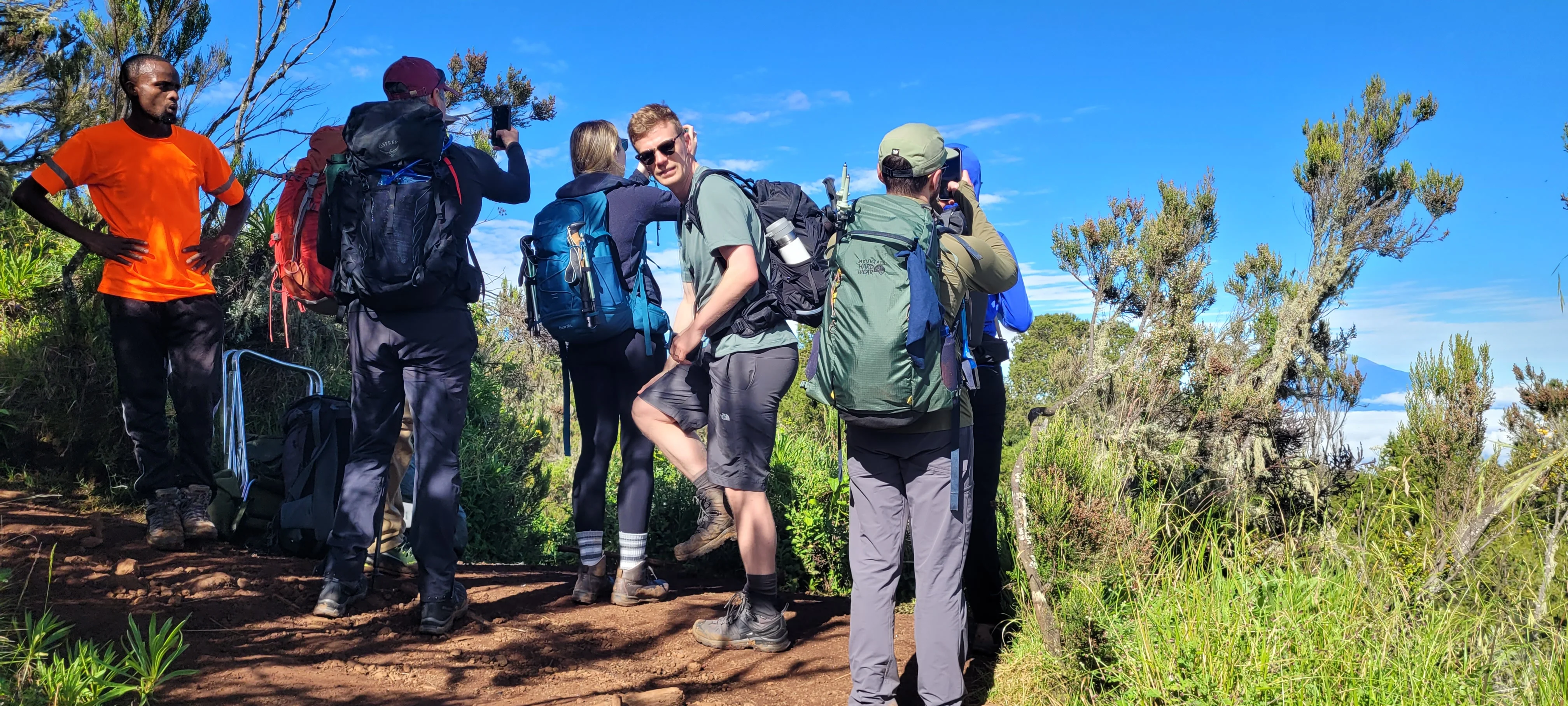 Hikers pause on Mount Kilimanjaro trail among alpine vegetation during a scenic trekking adventure in northern Tanzania hike.