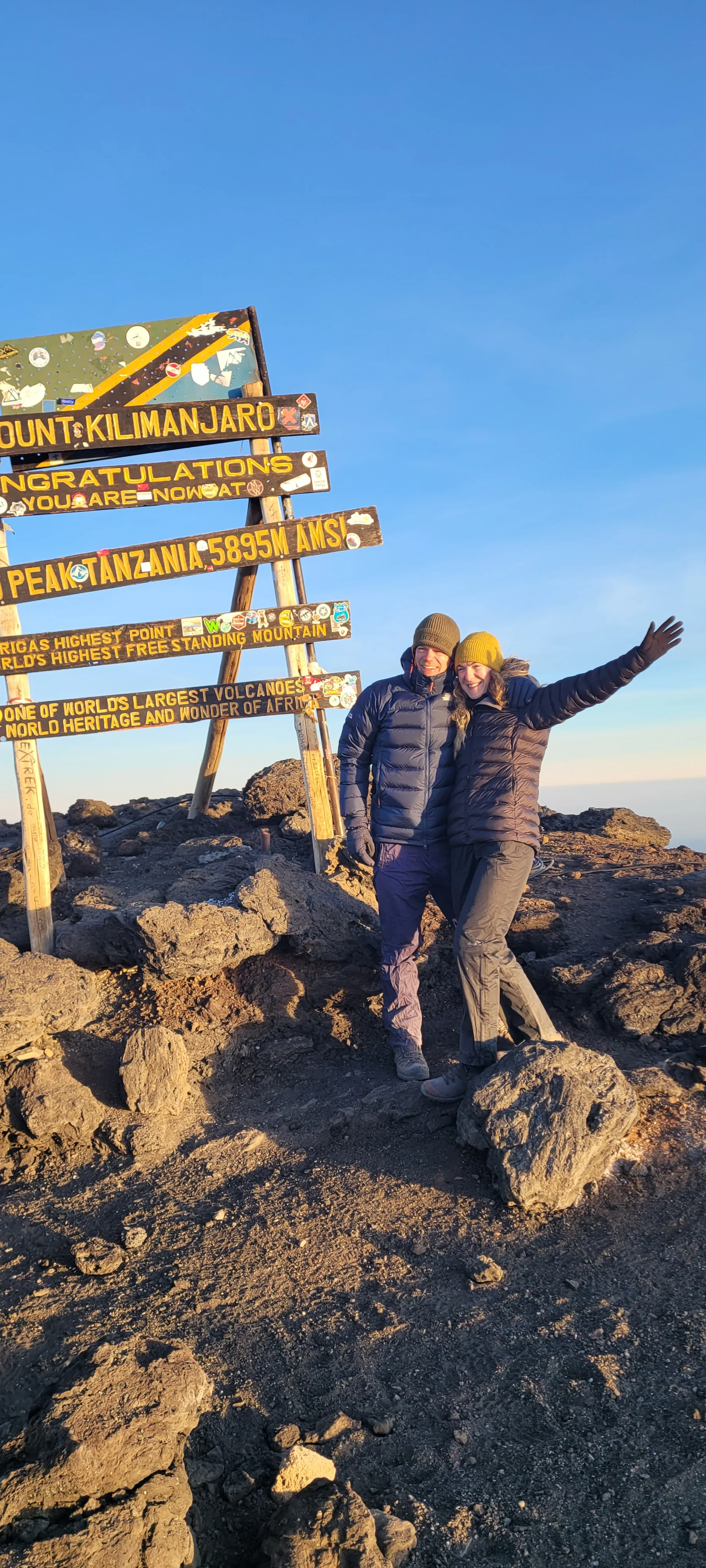 Trekkers celebrate at Uhuru Peak on Mount Kilimanjaro beneath the summit sign after completing a demanding climb in Tanzania.