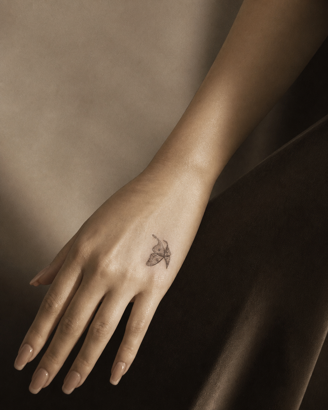 An AI-generated editorial image of an anonymous hand with a small fine-line butterfly tattoo near the thumb.
