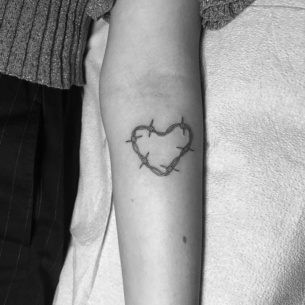 Black-and-white source photograph showing Dua Lipa's barbed-wire heart on her inner forearm