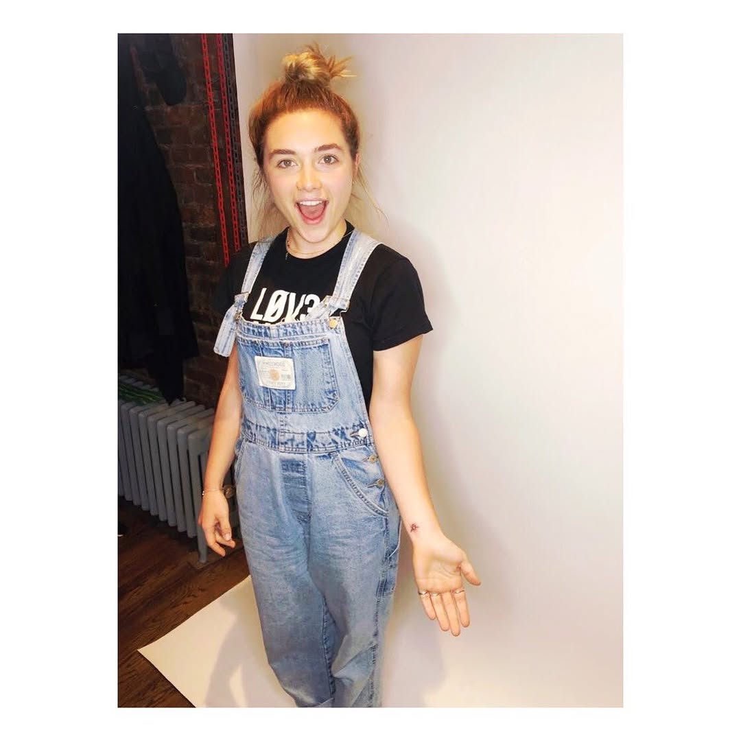 Florence Pugh extending her left hand to show the small worker bee tattoo on her inner wrist