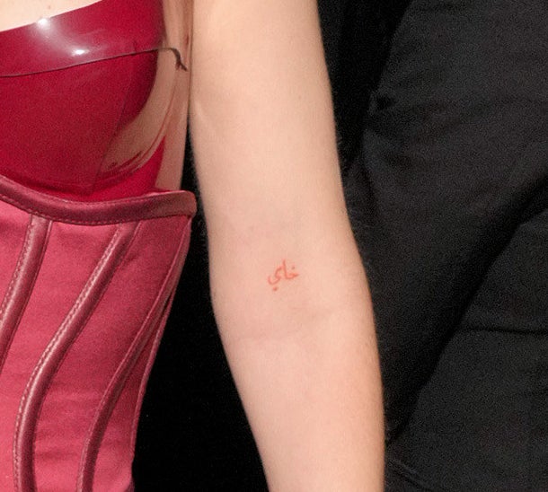 Gigi Hadid's right inner arm with a small red Arabic-script tattoo just above the elbow