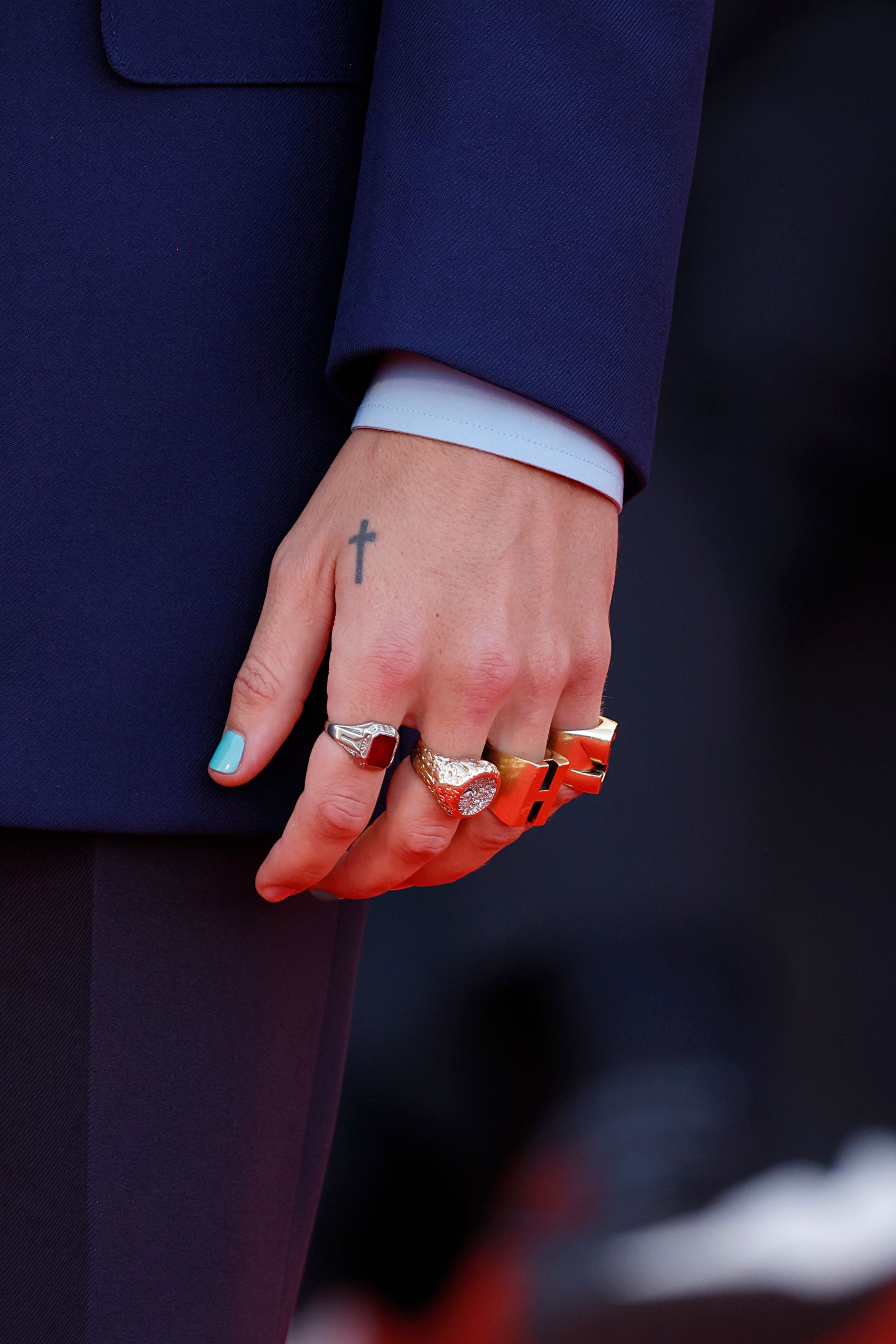 Harry Styles' left hand at the 2022 Venice photocall, with a small black cross between the thumb and index finger
