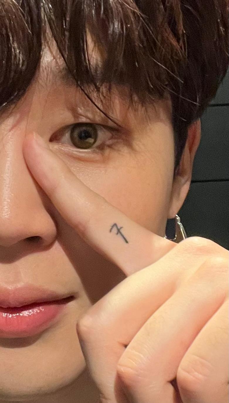 Jimin holds up his index finger beside his face, showing the small black seven on its side.
