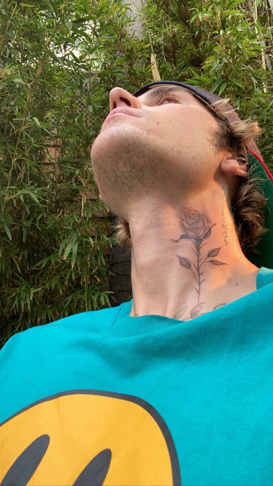 Justin Bieber tilts his head back to show the black-and-gray rose on the right side of his neck