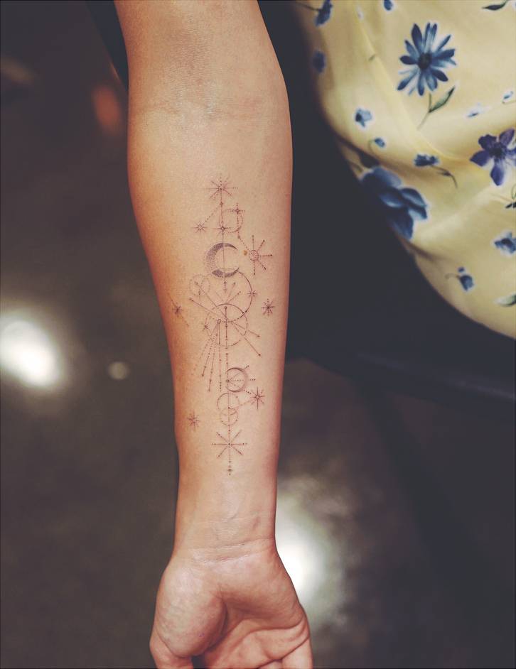 Full right-inner-forearm view of Olivia Wilde’s fine-line celestial constellation tattoo